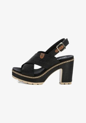 Sandalias de plataforma negras con textura trenzada, correa con hebilla ajustable y un alto tacón cuadrado con costura de suela beige.