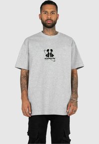 Grå bomull t-skjorte med korte ermer, med et svart grafisk logo på brystet. Stoffet har en myk tekstur, og passformen er avslappet.