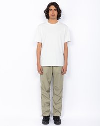 Biała bawełniana koszulka z okrągłym dekoldem i subtelnym logo, sparowana z jasnymi, khaki spodniami cargo z bocznymi kieszeniami i zatrzaskami.