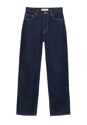 Gros plan d'une personne portant un jean taille haute bleu foncé, une main posée dans la poche avant et l'autre sur le côté.