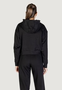 Hoodie noir raccourci avec une capuche double épaisse, des poignets et une taille côtelés. Texture douce et coupe décontractée, présenté de dos.