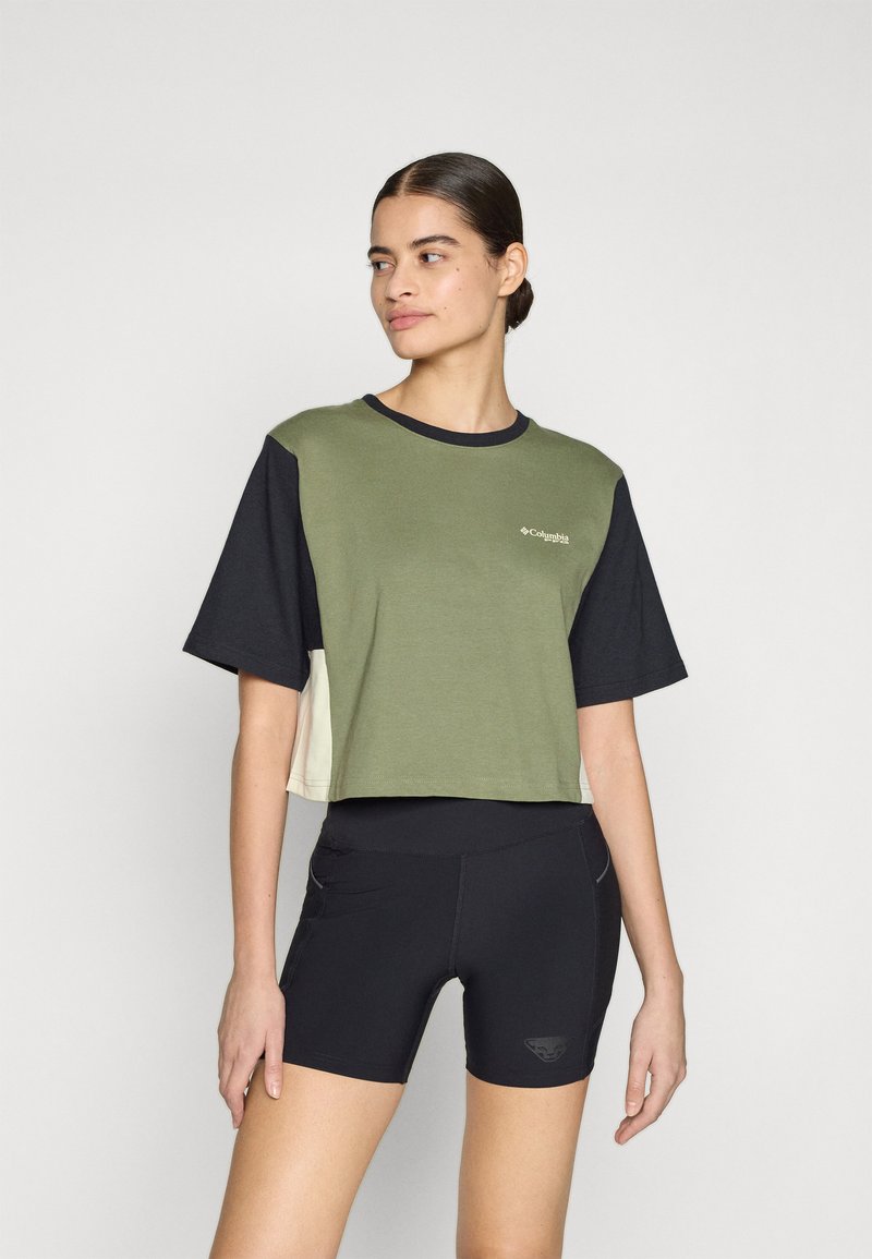 T-shirt cropped con blocchi di colore verde, nero e beige, maniche corte e un logo sul petto. Abbinato a pantaloni corti neri.