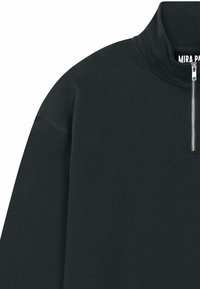 Pull-over noir avec un col montant, doté d'une fermeture éclair argentée au niveau du cou. Confectionné dans un tissu lisse avec une coupe décontractée et sans motifs.
