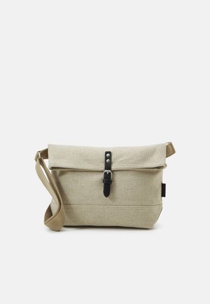 Beige Canvas-Umhängetasche mit verstellbarem Riemen und Vorderklappe, die durch eine schwarze Lederschnalle gesichert ist.