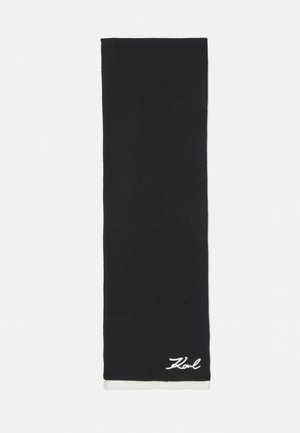 Black knitted scarf with white accent at the bottom, featuring a cursive "Karl" logo. Rectangular shape with a ribbed texture.
