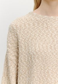 Beiger Pullover aus strukturiertem Strickstoff, mit Rundhalsausschnitt und lockerer Passform, sowie dezenten erhabenen Mustern im gesamten Design.