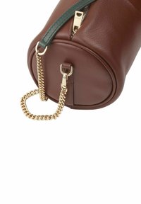 Borsa a cilindro in pelle marrone con una tracolla verde, hardware dorato e un dettaglio a catena spessa. Apertura con zip nella parte superiore.