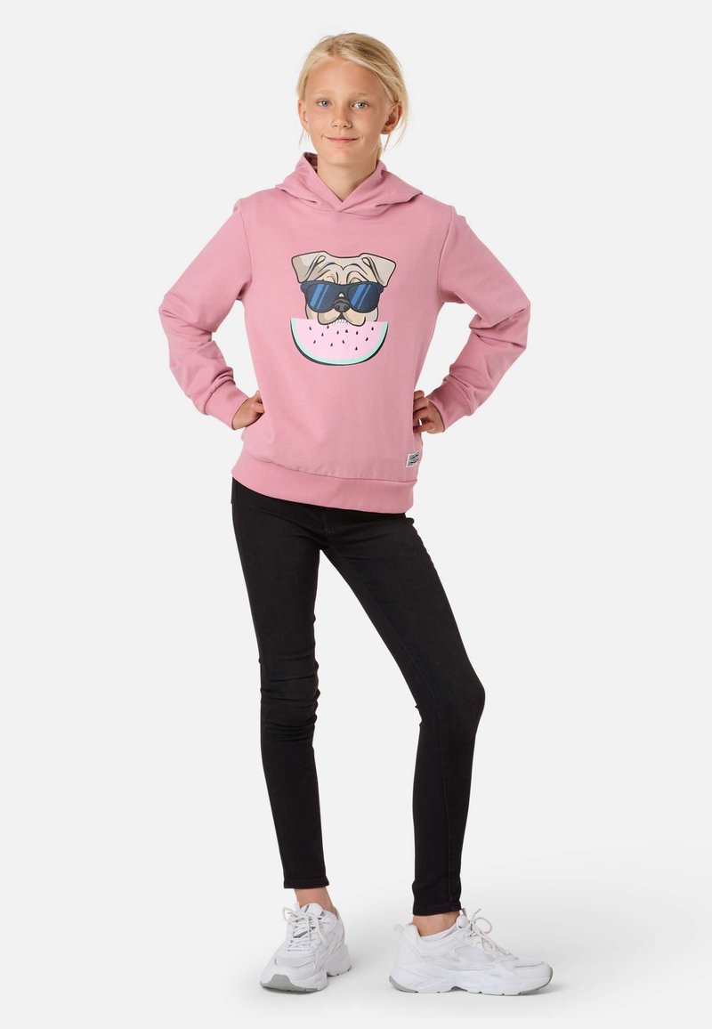 Rosa hoodie med en hundillustration med solglasögon, tillsammans med svarta leggings och vita sneakers. Enkelt mönster, mjukt tyg.