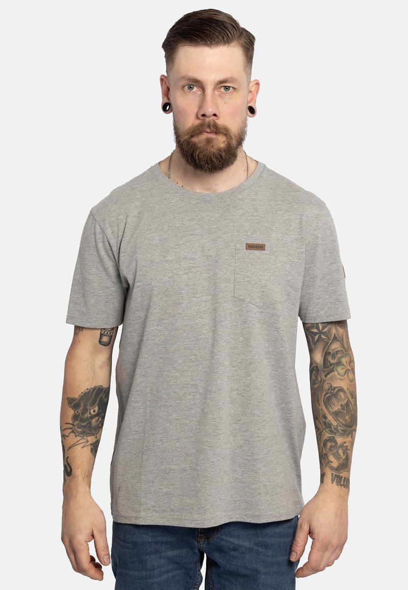T-shirt in cotone grigio con maniche corte, colletto rotondo e tasca sul lato sinistro del petto. Dettaglio distintivo con etichetta marrone sulla tasca. Vestibilità casual.