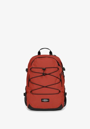 Zaino in nylon rosso con accenti neri, corde elastiche regolabili sul davanti, tasche laterali in rete e una maniglia superiore per il trasporto.