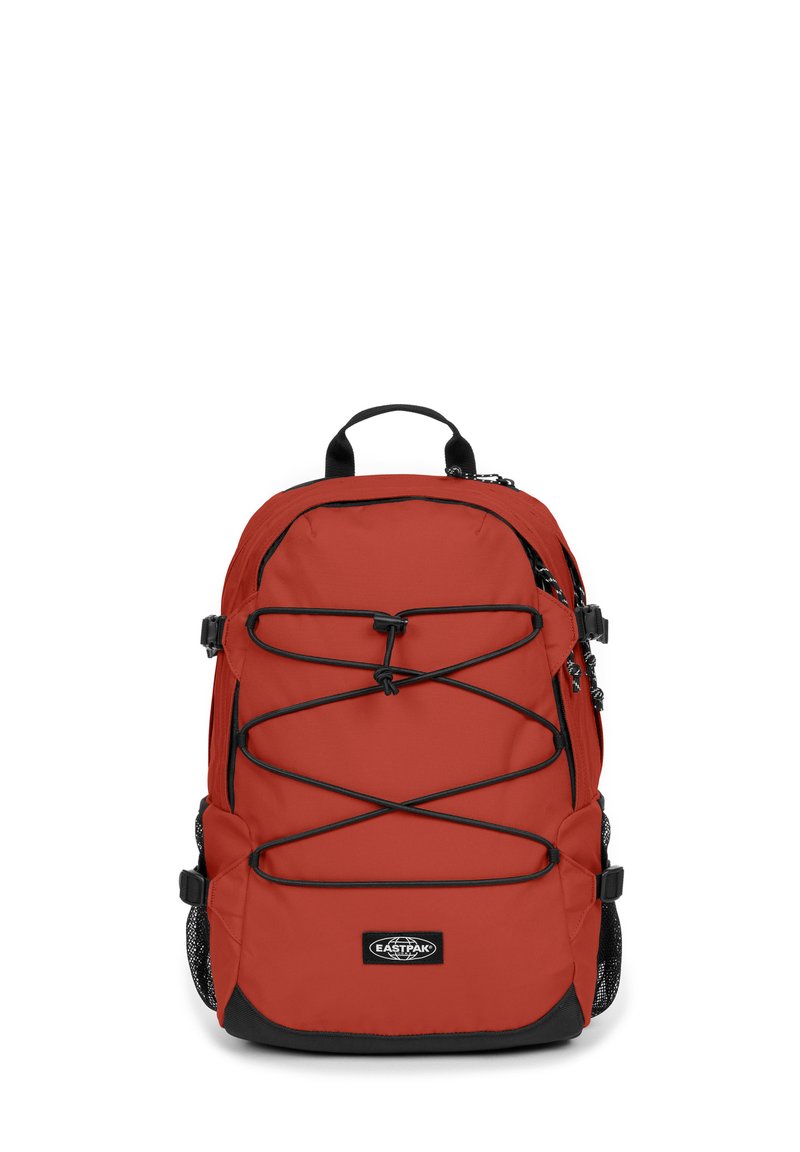 Rød nylon rygsæk med sorte detaljer, justerbare bungee-snore på forsiden, side mesh-lommer og et håndtag til at bære i toppen.