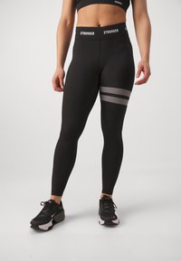 Leggings neri in tessuto elastico con vita alta, caratterizzati da dettagli a strisce argento e una texture liscia.