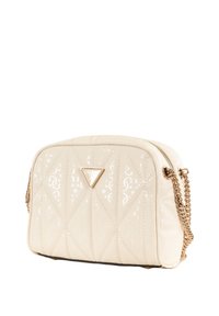 Borsa a tracolla crema trapuntata con finitura lucida, catena dorata e dettaglio logo triangolare sul davanti; presenta una chiusura a zip.