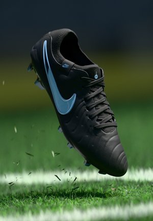 Black Nike football boot with a sleek design, textured surface, and a light blue swoosh. Features studs and is shown above grass.