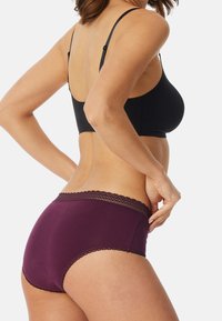 Svart bh och djupt burgunderfärgade trosor med spetsdetaljer. Bh:n har justerbara band och trosorna har en slät yta och full täckning.
