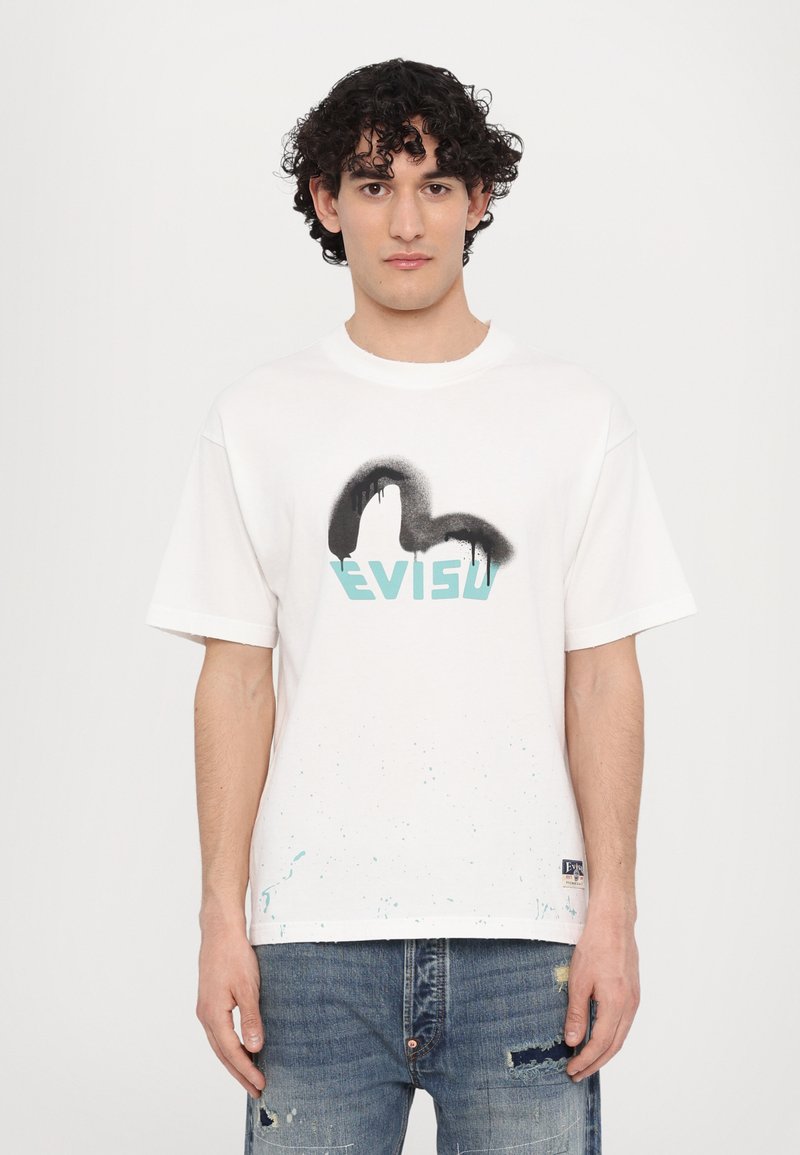 Baltos medvilnės marškinėliai su juodu purškimo dizainu ir turkio spalvos "EVISU" logotipu. Mėlynos spalvos purškimo akcentai puošia apatinį hemą.