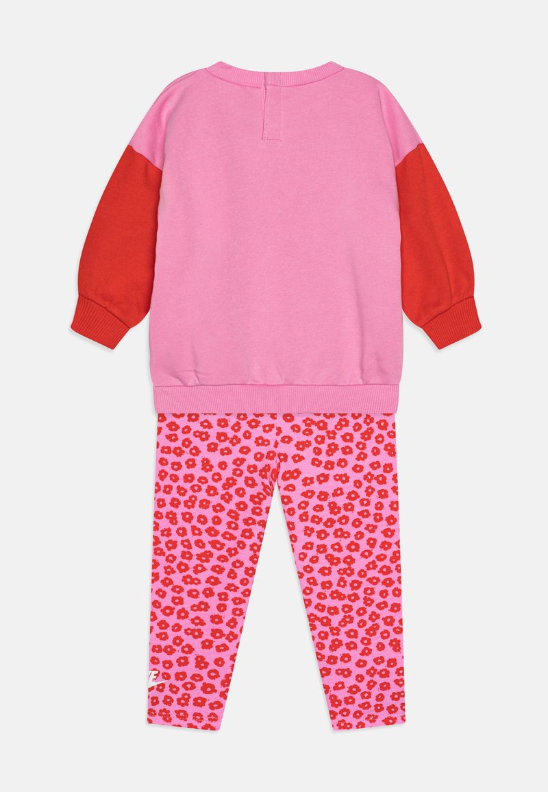 Felpa di cotone con maniche a blocchi di colore rosa e rosso, abbinata a leggings rosa con un motivo floreale rosso.