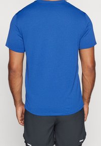 Camiseta de hombre de manga corta en azul brillante, confeccionada con tela lisa, con cuello redondo y costuras planas. Ligera y con un ajuste relajado.