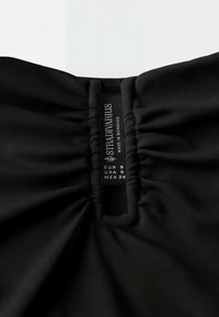 Vêtement noir avec encolure élastique froncée et étiquette visible de la marque Stradivarius indiquant la taille small pour l'Europe, les États-Unis et le Mexique.