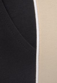 Oberteil aus Baumwollmischung mit einem Farbblockdesign in Schwarz, Creme und Beige. Textil mit sichtbaren Nähten und strukturiertem Stoff.