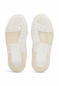 Sneaker bianchi con suole in gomma testurizzata. Le caratteristiche includono accenti circolari, una sezione trasparente e motivi a rilievo per una migliore aderenza.