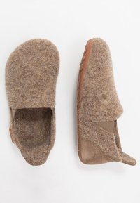Chaussons en feutre marron avec semelles en caoutchouc, avant arrondi et panneaux latéraux élastiques pour un enfilage facile. Texture douce avec des détails de couture minimaux.
