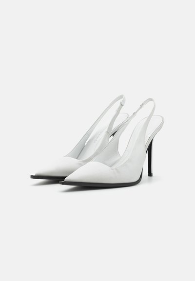 Vita slingback-hälar med spetsig tå, tillverkade av mjukt material, med en svart klack och minimalistisk design utan synliga mönster.
