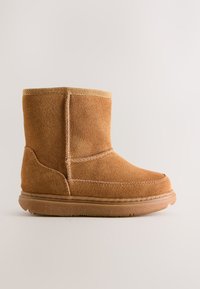 Gheată de gleznă din piele întoarsă cămilă, cu vârf rotund, guler moale din material textil și talpă de cauciuc. Detaliu cusut de-a lungul cusăturilor.