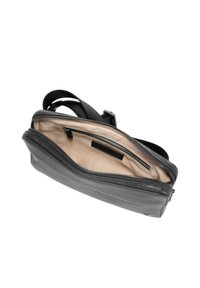 Borsa nera in pelle con chiusura a cerniera. Interno con fodera beige e una piccola tasca con zip. Tracolla regolabile. Forma compatta.