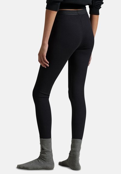 Černé legíny s žebrovanou strukturou a elastickým pasem. Nosit s šedými, žebrovanými ponožkami s malým logem blízko lemu.