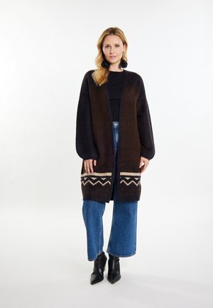 Hnědý a námořnický oversized cardigan s dlouhými rukávy, zdobený geometrickým vzorem v krémové barvě na lemu, spárovaný s džíny s širokým střihem.