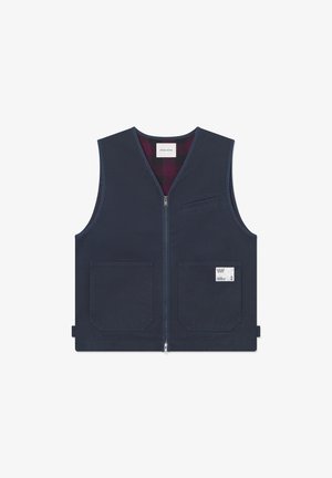 Vest fără mâneci, de culoare albastru închis, cu fermoar în față, două buzunare frontale și o căptușeală în carouri. Include un eticheta a brandului pe buzunar.