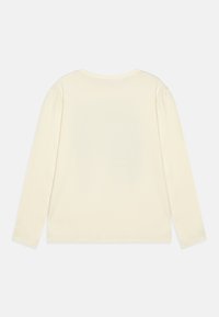 Haut à manches longues de couleur crème, avec un col rond, en coton doux, et une coupe décontractée sans motifs ni accents visibles.