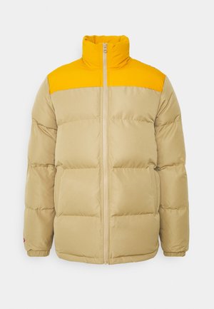 Chaqueta de plumas beige con yugo amarillo brillante, cremallera frontal, cuello alto, mangas acolchadas y puños elásticos, exhibida sobre fondo blanco.