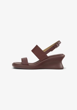 Brauner Keilsandalette mit zwei breiten Riemen und verstellbarem Schnallenriemen auf einer geschwungenen Sohle, Seitenansicht vor weißem Hintergrund.