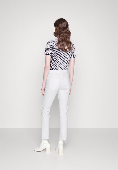 Svart og hvit tie-dye t-skjorte med korte ermer, hvite høyhårede jeans og hvite block-heeled ankelstøvler. Glatt stoff, slank passform, revne kanter.