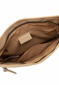 Khakifarbene Reißverschluss-Tasche mit glatter Außenseite; verfügt über Innentaschen, hellbeige Innenfutter und ein Logo-Tag. Reißverschlussverschluss oben.