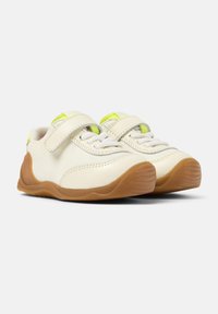 Sneaker leggere con tomaia in tela color crema, dettagli gialli e cinturino in velcro. La soletta in gomma offre aderenza e durata.