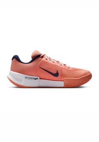 Nike sneakers har et ferskenfarvet tekstiloverdel, marineblå accenter, hvide snørebånd og en skridsikker sål med teksturerede detaljer. Logoet er placeret på siden.