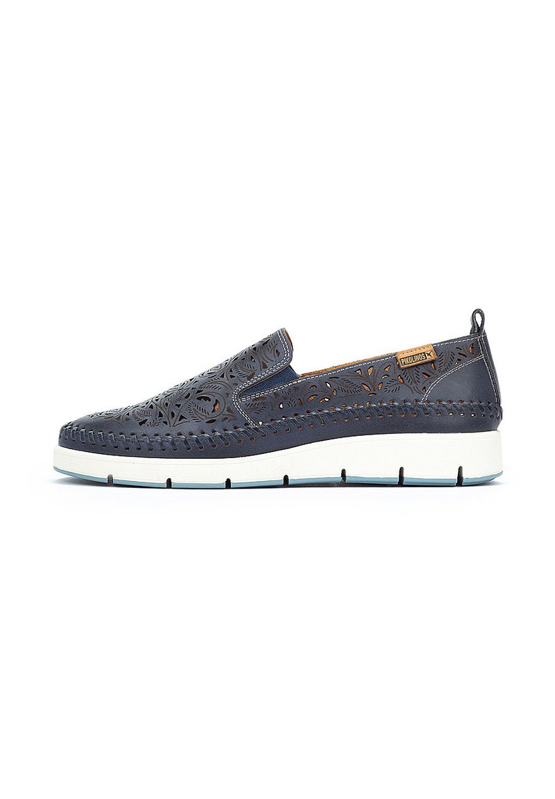 Zapato sin cordones de piel azul marino con patrón floral recortado, suela intermedia blanca y acento beige. Presenta detalles cosidos y una lengüeta trasera.