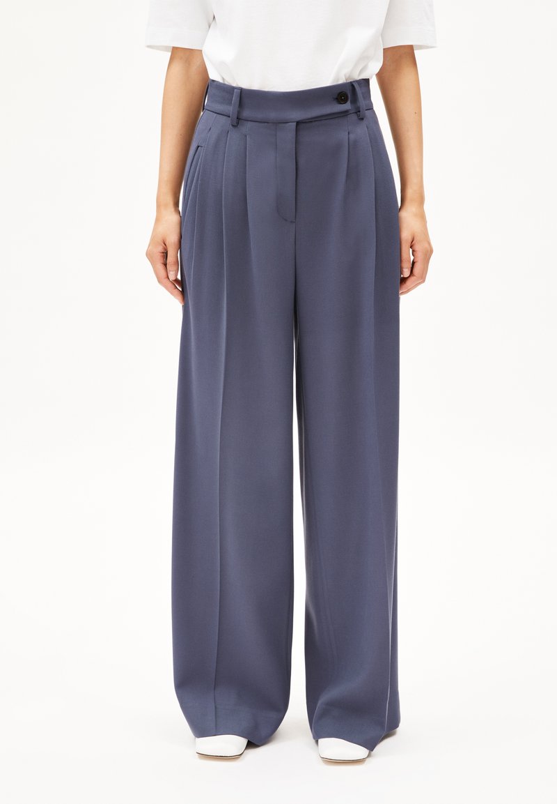 weite Hosen in Marineblau, mit hoher Taille, Gürtelschlaufen, vorderen Falten und Knopfverschluss. Glattes Material mit leichtem Glanz.