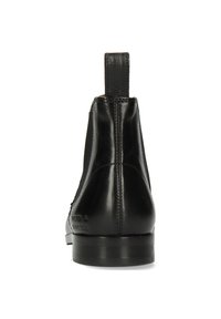 Botines Chelsea de cuero negro con paneles laterales elásticos, punta redonda, tacón elevado y un lazo para facilitar su colocación. Textura suave, con un diseño minimalista.