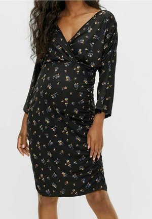 Zwarte jurk met een V-hals, lange mouwen en geplooide zijkanten. Beschikt over een bloemenpatroon in blauw en geel op een gestructureerde stof.