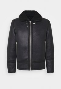 Svart läderjacka med en texturerad yta, utrustad med en svart shearlingkrage, två dragkedjefickor på sidan och dragkedja fram.