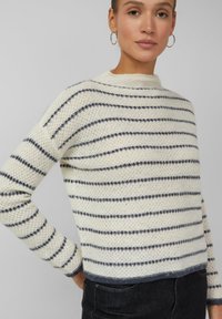 Leichter, gestrickter Pullover in Creme mit marineblauen Streifen. Rundhalsausschnitt, lange Ärmel und dezentes Strukturmuster. Kurze Länge mit geripptem Saum.