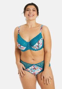 Soutien-gorge en dentelle teal et culottes assorties avec un motif floral. Le soutien-gorge possède des bords festonnés et un noeud décoratif au centre. Texture lisse, ajustement confortable.