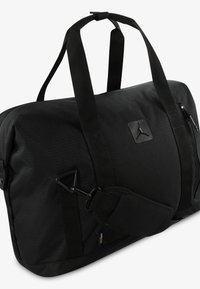 Bolsa de deporte negra hecha de un tejido duradero, con un logotipo destacado, doble asa, correa de hombro ajustable y bolsillos con cremallera.