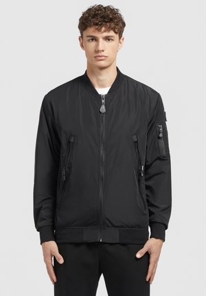 Schwarze Bomberjacke mit einem Reißverschluss vorne, gerippten Bündchen und zwei seitlichen Reißverschlusstaschen. Hergestellt aus glattem, leichtem Stoff mit einem minimalistischen Design.
