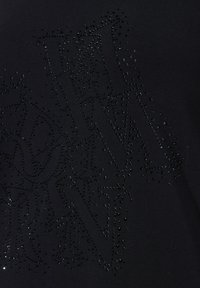 Černé tričko z látky s texturou kamínků tvořících písmena, s hladkým, lesklým povrchem a přiléhavým střihem.