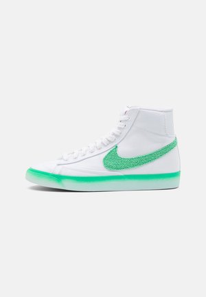 Zapatilla blanca de caña alta con logo de swoosh texturizado en verde y suela a juego en degradado verde.